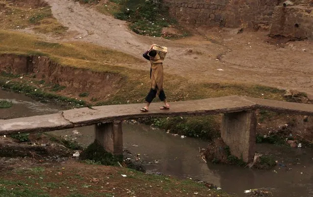 A man carries a fruit crate while crossing a bridge in a slum on the outskirts of Islamabad January 21, 2015. (Photo by Faisal Mahmood/Reuters)