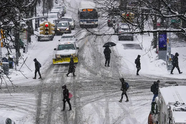 Pedestrians cross 71st Avenue as snow falls Thursday, February 18, 2021, in the Queens borough of New York. (Photo by Frank Franklin II/AP Photo)