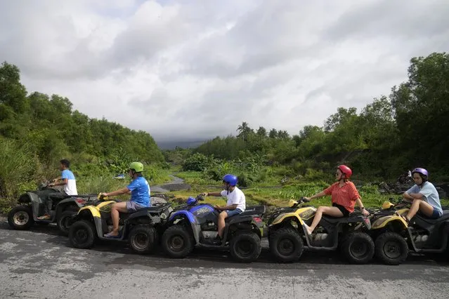 Tourists ride ATV's near Mayon Volcano, hidden in clouds, in Daraga, Albay province, northeastern Philippines on Sunday, June 11, 2023. (Photo by Aaron Favila/AP Photo)