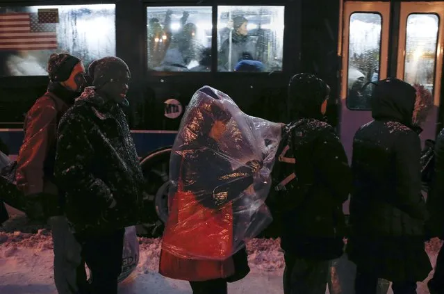 People wait in line for a public bus during snowfall in the Queens borough of New York January 26, 2015. As a powerful blizzard bore down on the northeastern United States on Monday, airlines, commuter rail, bus lines and subways responded with travel delays and cancellations. (Photo by Shannon Stapleton/Reuters)