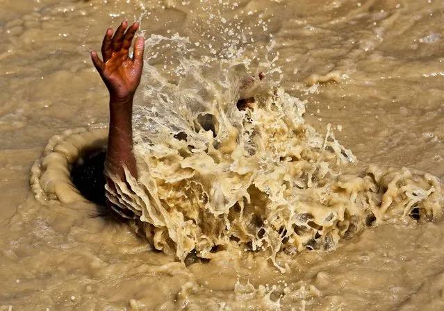 A boy swims in the muddy waters in Kabul, Afghanistan, on July 16, 2013. (Photo by Omar Sobhani/Reuters)