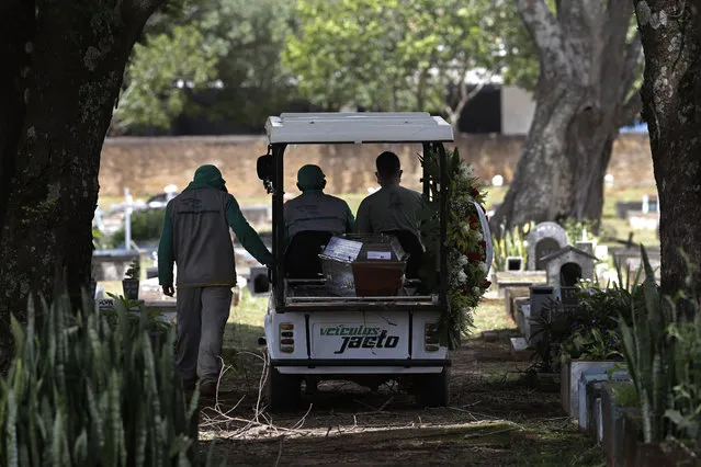 Cemetery workers transport the coffin that contains the remains of Jose Valdelirio believed to have died from the new coronavirus, to a burial site at the Campo da Esperanca cemetery in the Taguatinga neighborhood of Brasilia, Brazil, Wednesday, March 3, 2021. The number of COVID-19 cases in Brazil is still surging, with a new record high of deaths reported on Tuesday. (Photo by Eraldo Peres/AP Photo)