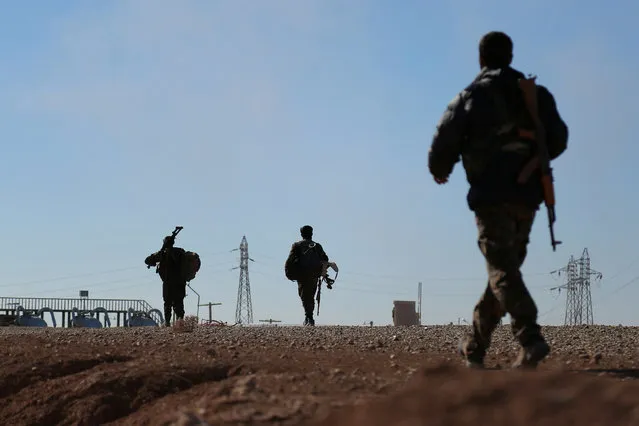 Syria Democratic Forces (SDF) fighters carry their weapons as they walk near the town of Tel al-Saman in the northern rural area of Raqqa, Syria November 17, 2016. (Photo by Rodi Said/Reuters)