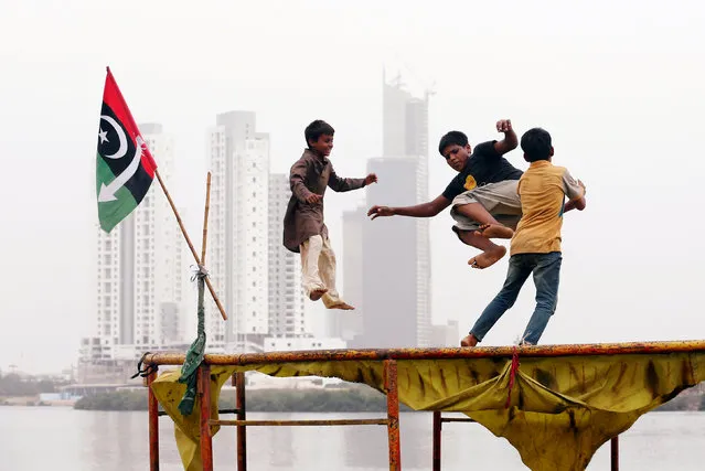 Children play on a trampoline, near electoral flag of a political party, with the under-construction buildings in the background, in a low-income neighborhood in Karachi, Pakistan July 18, 2018. (Photo by Akhtar Soomro/Reuters)