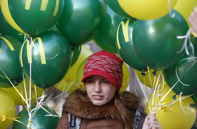 A teenager holds balloons outside a McDonald's restaurant on the day of its reopening in central Moscow, Russia November 19, 2014. McDonald's Corp. will open fewer new restaurants in Russia in 2015 because a fall in the rouble has increased expansion costs and is hurting consumers, its Russian chief executive Khamzat Khasbulatov told Reuters. (Photo by Sergei Karpukhin/Reuters)