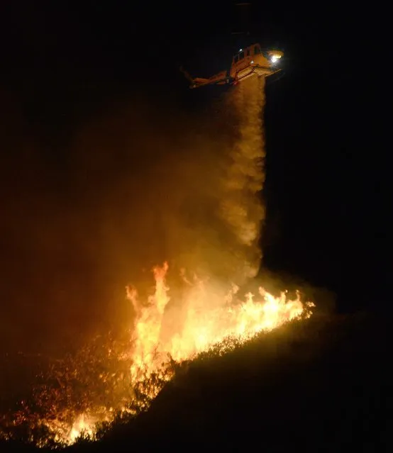 A helicopter makes a water drop on the Solimar  brush fire that started early Saturday morning in Ventura County, California December 26, 2015. (Photo by Gene Blevins/Reuters)