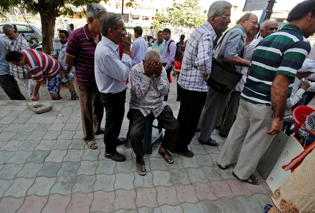 A man sits in a queue to deposit or exchange his old high denomination banknotes outside a bank in Ahmedabad, India November 21, 2016. (Photo by Amit Dave/Reuters)