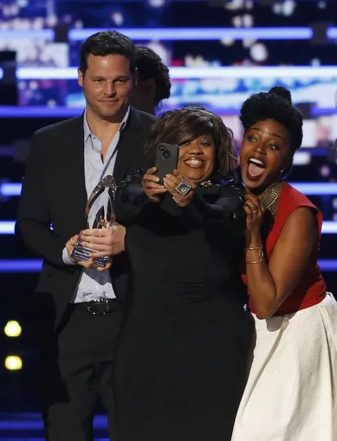 "Grey's Anatomy" cast members Chandra Wilson (C) and Jerikka Hinton take a selfie as fellow cast member Alex Karev watches as the cast accepts the award for favorite network TV drama series at the People's Choice Awards 2016 in Los Angeles, California January 6, 2016. (Photo by Mario Anzuoni/Reuters)