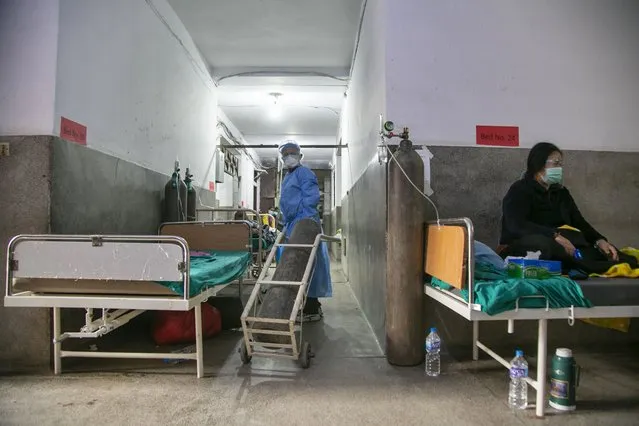 A Nepalese paramedic wheels in an oxygen cylinder as a COVID-19 patient rests on a bed in the corridor of a government run hospital in Kathmandu, Nepal, Friday, May 7, 2021. (Photo by Niranjan Shrestha/AP Photo)