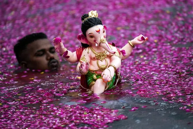 A man prepares to immerse in an artificial pond, an idol of elephant headed Hindu god Ganesha on the second day of ten days long Ganesh Chaturthi festival in Mumbai, India, Wednesday, September 20, 2023. (Photo by Rajanish Kakade/AP Photo)