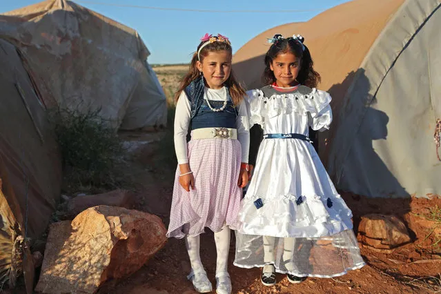 Displaced Syrian girls in holiday dresses pose for a picture in front of a tent in the Tah camp for internally displaced persons (IDP) in Syria's rebel-held northwestern province of Idlib on May 13, 2021, on the first day of the Eid al-Fitr holiday, which marks the end of the holy fasting month of Ramadan. (Photo by Omar Haj Kadour/AFP Photo)