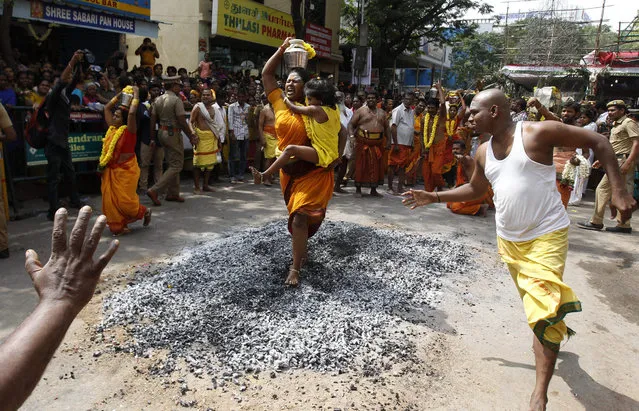 A Hindu devotee carrying her child,walks on burning coal during a religious procession marking Thaipusam festival in Chennai, India, Sunday, January 24, 2016. Thaipusam, which is celebrated in honor of Hindu god Lord Murugan, is an annual procession by Hindu devotees seeking blessings, fulfilling vows and offering thanks. (Photo by Arun Sankar K./AP Photo)