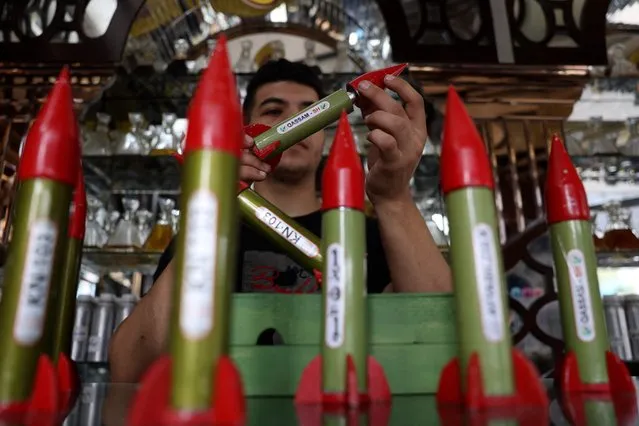 An employee handles bottles of perfume shaped like locally made Qassam rockets, sold in a shop in Gaza City on October 4, 2023. (Photo by Mohammed Abed/AFP Photo)