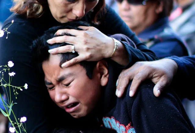 People cry during a mass for the victims of the fireworks market explosion in Tultepec, Mexico state, on December 22, 2016. Mexico worked on the eve to identify charred bodies left by an explosion that killed at least 33 people at its biggest fireworks market, as authorities investigated what caused the multi-colored salvo of destruction. Rescue workers were still searching for bodies – or survivors – in the smoldering wreckage of the San Pablito market. (Photo by Pedro Pardo/AFP Photo)