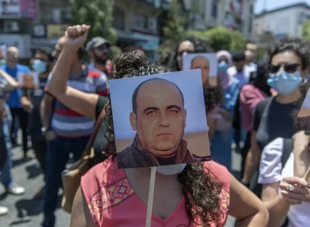 Angry demonstrators carry pictures of Nizar Banat, an outspoken critic of the Palestinian Authority, and chant anti-PA slogans during a rally protesting his death, in the West Bank city of Ramallah, Thursday, June 24, 2021. (Photo by Nasser Nasser/AP Photo)