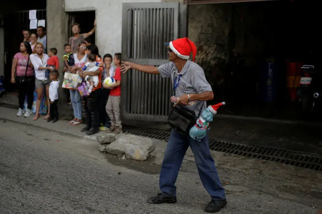 A man wearing a Santa Claus hat helps to control traffic in exchange for money along a street of Petare slum in Caracas, Venezuela December 20, 2016. (Photo by Marco Bello/Reuters)