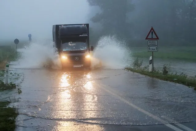 A vehicle travels on a flood affected road after the Erft river swelled following heavy rainfalls in Erftstadt, near Cologne, Germany, July 15, 2021. (Photo by Wolfgang Rattay/Reuters)