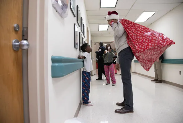 This photograph, obtained courtesy of the Obama Foundation, shows former US President Barack Obama delivering gifts, greeting patients and their parents at Children’s National Medical Center in Washington, DC, December 19, 2018. (Photo by Chuck Kennedy/AFP Photo)