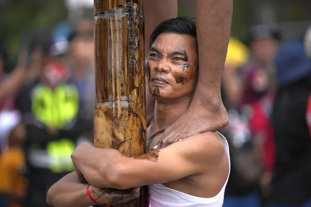 A participant bears the weight of other men above him as people climb greased poles to retrieve prizes during a greased-pole climbing competition held as a part of Independence Day celebrations at Ancol Beach in Jakarta, Indonesia Wednesday, August 17, 2022. Indonesia is celebrating its 77th anniversary of independence from the Dutch colonial rule. (Photo by Tatan Syuflana/AP Photo)