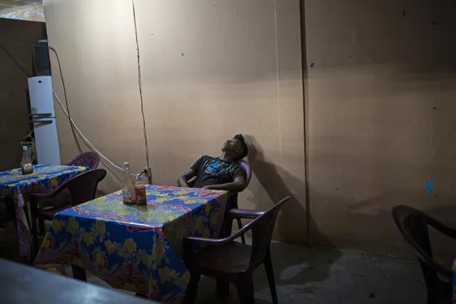 In this February 9, 2018 photo, a man takes a nap inside a makeshift restaurant in Puerto Lempira, Honduras. With more than 60 per cent of its 9 million population living in poverty, Honduras is one of the poorest countries in Latin America, and the Mosquitia is one of the most impoverished areas. (Photo by Rodrigo Abd/AP Photo)