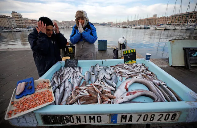 Fishmongers try to keep warm in front of their fish stall during a cold winter's day at the Old Harbour in Marseille, France, January 18, 2017. (Photo by Jean-Paul Pelissier/Reuters)