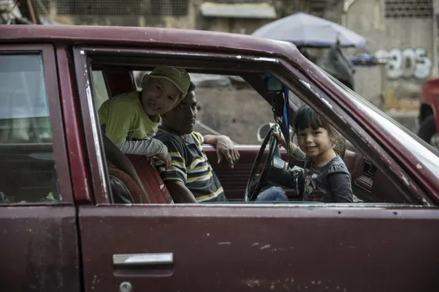 A family waits inside a car near the Quinta Crespo street market downtown in Caracas, Venezuela, Saturday, January 26, 2019. The country's political showdown moves to the United Nations Saturday where a Security Council meeting called by the United States will pit backers of President Nicolas Maduro against the Trump administration and supporters of the country's self-declared interim leader Juan Guaido. (Photo by Rodrigo Abd/AP Photo)