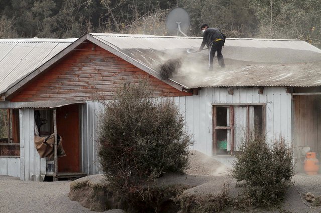 A man shovels ash from Calbuco volcano off the roof of his home in Ensenada, April 23, 2015. (Photo by Carlos Gutierrez/Reuters)
