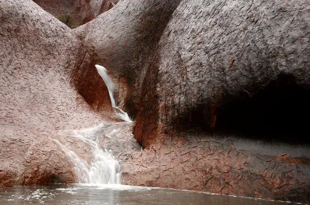Water runs off Uluru in Mutitjulu Waterhole as it rains on November 28, 2013 in Uluru-Kata Tjuta National Park, Australia. Uluru/ Ayers Rock is a large sandstone formation situated in central Australia approximately 335km from Alice Springs. The site and its surrounding area is scared to the Anangu people, the Indigenous people of this area and is visited by over 250,000 people each year.  (Photo by Mark Kolbe/Getty Images)