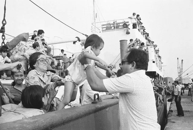 Father and mother, from front and back, help lift their youngster from ship to dock as the family and hundreds of other refugees arrive at Saigon dock, Friday, March 29, 1975. The arrival of the merchant vessel was one of the first at the capital since the mass exodus of South Vietnamese from the central highlands and Northern provinces. (Photo by AP Photo/Phuoc)