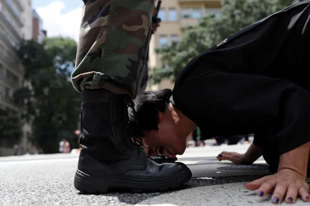 Venezuelan artist Deborah Castillo licks the boots of a man dressed as a member of the military during her performance “Lamebrasil, Lamezuela – questioning power in Latin America”, in Sao Paulo, Brazil, March 24, 2019. (Photo by Amanda Perobell/Reuters)