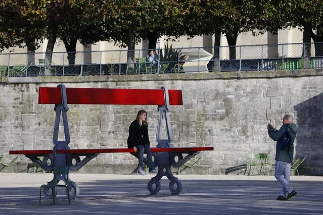 A woman sits on “Double Banc”, artwork by French artist Lilian Bourgeat as part of the FIAC, the French International Contemporary Art Fair, in the Jardin des Tuileries in Paris, on October 21, 2021. The French International Contemporary Art Fair (FIAC), which took place virtually in March because of Covid, returns in real life and online from October 21-24, accompanied by its little sister dedicated to Asia, Asia Now. (Photo by Thomas Samson/AFP Photo)