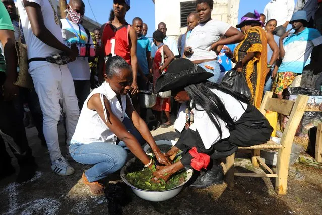 A woman's hands are bathed in a mixture said to bring good luck at a cemetery during Day of the Dead celebrations, in Port-au-Prince, Haiti on November 1, 2021. (Photo by Ralph Tedy Erol/Reuters)