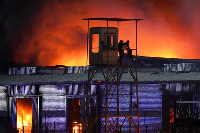 Security guards watch a large fire consuming an industrial sector in the Pudahuel district of Santiago, Chile on February 20, 2024. (Photo by Matias Basualdo/ZUMA Press Wire/Rex Features/Shutterstock)