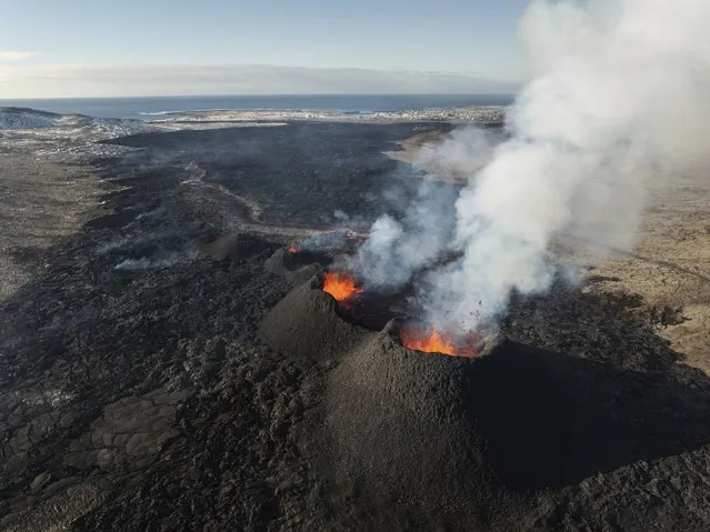 The eruption area is seen with the town of Grindavik in the background, on Iceland, Thursday, March 28, 2024. The volcano in southwestern Iceland that erupted three times in December, January and February, sending lava towards a nearby community, keeps erupting. (Photo by Marco di Marco/AP Photo)