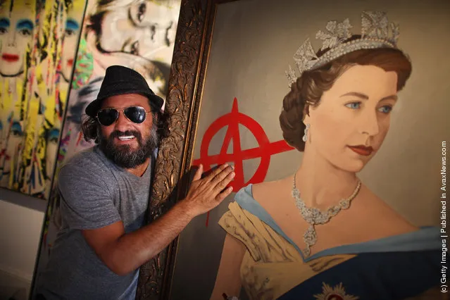 Artist Mr Brainwash stands with his paintings 'The Queen' (R) and 'Kate Moss' at the Opera Gallery