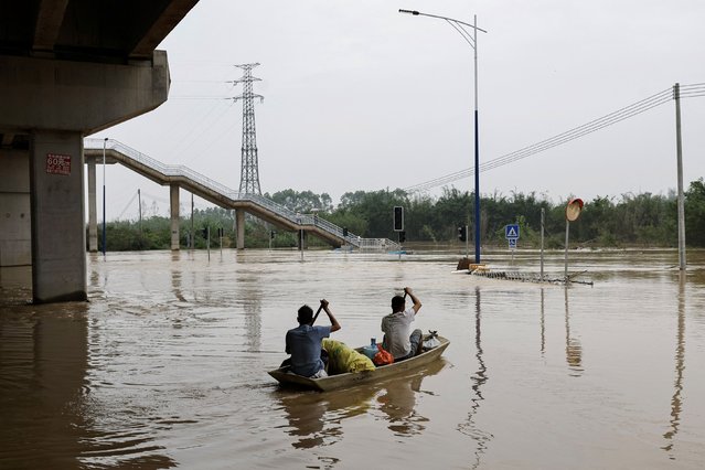 Residents row a boat on the floodwaters following heavy rainfall, at the Xiashahe village, in Qingyuan, Guangdong province, China on April 22, 2024. (Photo by Tingshu Wang/Reuters)