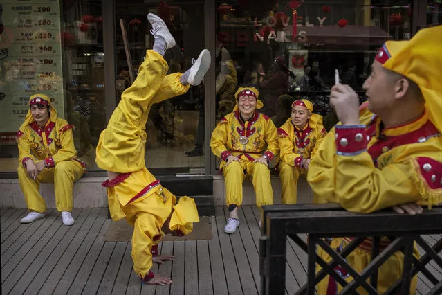 A Chinese dragon dancer does a handstand as he and other performers take a break while shooting a film in the Sanlitun area on April 3, 2014 in Beijing, China. The popular traditional dance is often performed during the annual Spring Festival at Chinese New Year. (Photo by Kevin Frayer/Getty Images)