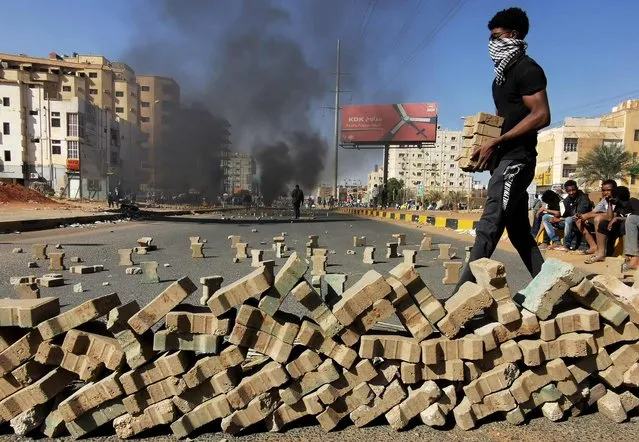 Protesters use bricks to block a street in the Sudanese capital Khartoum, during a demonstration against the killings of dozens in a crackdown since last year's military coup, as US diplomats pressed for an end to the violence, on January 20, 2022. The demonstrations were the latest since the October 25 coup led by General Abdel Fattah al-Burhan, which derailed a civilian-military power-sharing deal negotiated in the wake of the 2019 ouster of autocrat Omar al-Bashir. (Photo by Ashraf Shazly/AFP Photo)