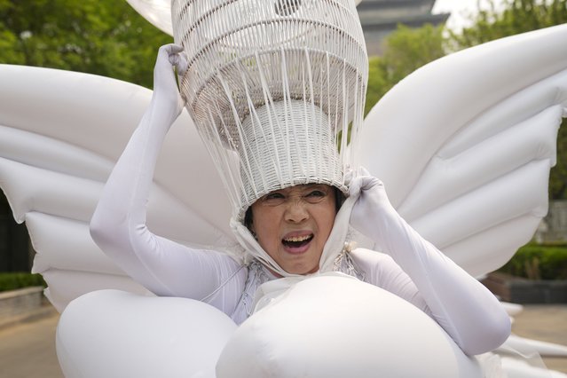 Artist Kong Ning makes a face as she adjusts the head gear of her “Transparent Earth¤ wearable installation, in commemoration of Earth Day in Beijing, China, April 22, 2024. (Photo by Tatan Syuflana/AP Photo)