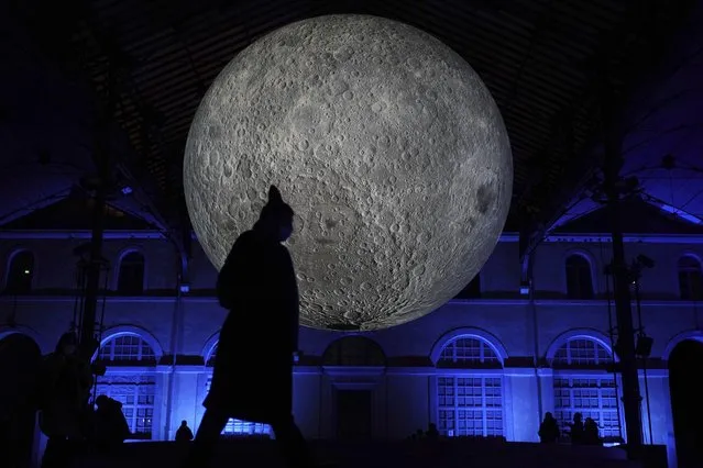 A man passes by a night light show in Lyon, central France, Wednesday, December 8, 2021. Millions of people are expected to experience the four-day Festival of Lights event in the city. (Photo by Laurent Cipriani/AP Photo)