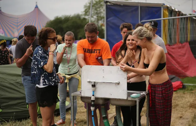Music fans wash at a water station during Glastonbury Music Festival on Friday, June 26, 2015 at Worthy Farm, in Glastonbury, England. (Photo by Joel Ryan/Invision/AP Photo)