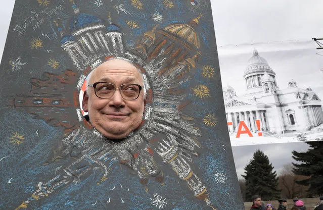 A man looks through a cardboard cutout poster during a protest rally against the decision of the city authorities to hand over the city's landmark St. Isaac's Cathedral to the Russian Orthodox Church in St. Petersburg, Russia, Saturday, March 18, 2017. About four thousand people gathered for a protest against the controversial return of the renowned cathedral to the Russian Orthodox Church. (Photo by Dmitri Lovetsky/AP Photo)