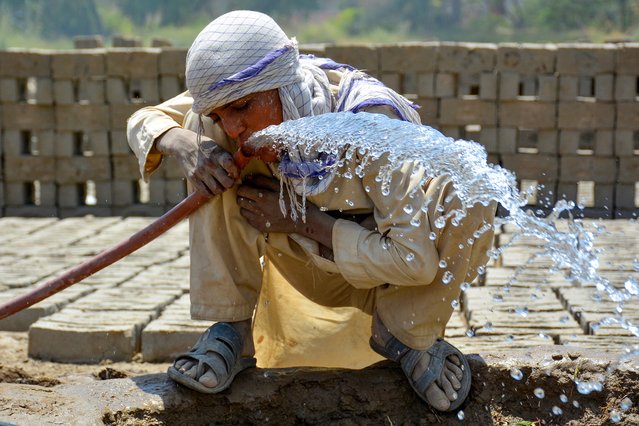 A labourer drinks water from a pipe at a brick kiln on a hot summer day in Sukkur, Sindh province on May 23, 2024. The Pakistan Meteorological Department said temperatures are expected to hit as high as 50 degrees Celsius (122 degrees Fahrenheit) in parts of rural Sindh. (Photo by Shahid Ali/AFP Photo)