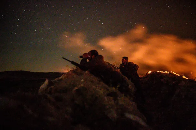 A fighter with the Syrian Democratic Forces (SDF) uses a binocular in a position in the eastern Syrian province of Deir Ezzor outside the Islamic State group's embattled holdout of Baghouz , on March 11, 2019. Kurdish-led forces pounded the last scrap of land held by the Islamic State group in eastern Syria after hundreds more people surrendered. The jihadists once ruled over millions in a swathe of Syria and Iraq, but they have since lost all that territory except for a riverside slither of land near the Iraqi border. (Photo by Bulent Kilic/AFP Photo)