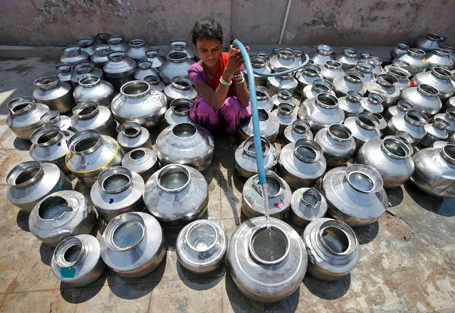 A girl fills metal pitchers with drinking water from a tubewell outside a temple in Ahmedabad, March 30, 2017. (Photo by Amit Dave/Reuters)