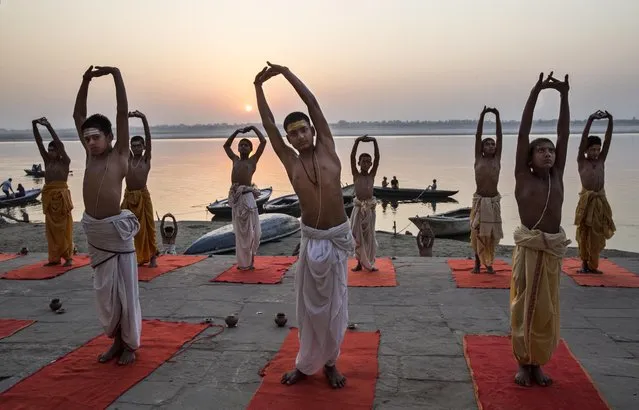 Young Indian Hindu Brahmins training to be priests perform yoga on a ghat on the Ganges River, holy to Hindus, at sunrise on April 23, 2014 in Varanasi, India. (Photo by Kevin Frayer/Getty Images)
