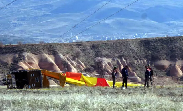 Security members investigate at the site after a hot air balloon hit a high-voltage transmission line and crashed near Cappadocia, a popular tourist destination in central Turkey, Sunday, April 9, 2017. The state-run Anadolu Agency says several hot air balloons lifted off Sunday in Turkey's Cappadocia region to give tourists a scenic view of the historic site, and one hit the electric line during its descent. (Photo by DHA-Depo Photo via AP Photo)