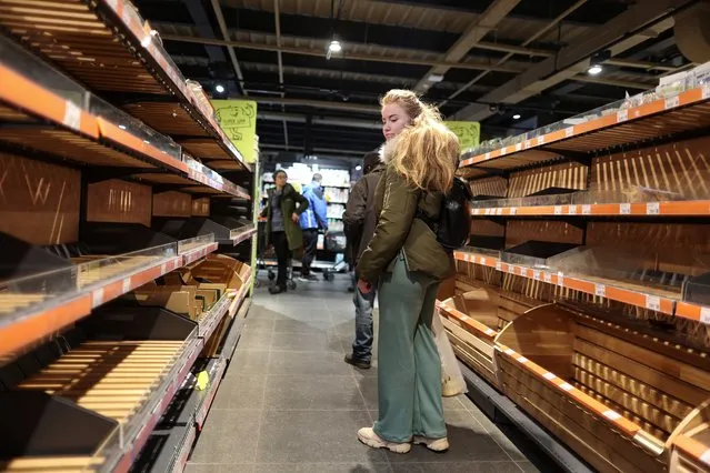 A woman looks at empty shelves of bread after the curfew was lifted as Russia's invasion of Ukraine continues, in Kyiv, Ukraine on February 28, 2022. (Photo by Carlos Barria/Reuters)