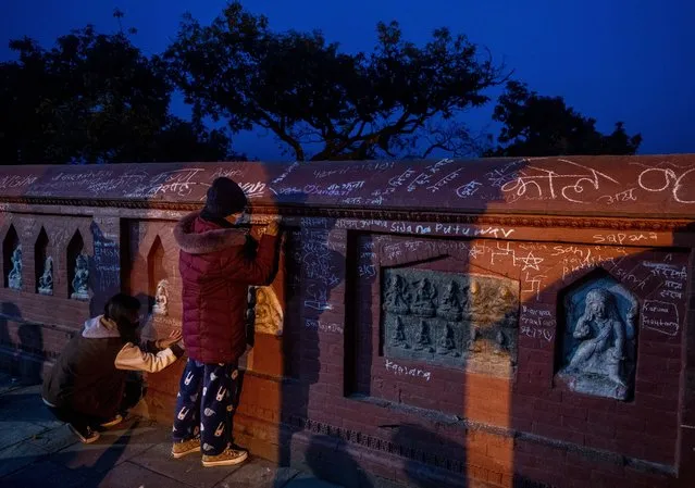 Nepalese children write their names on the wall of a Saraswati temple, during Shri Panchami festival in Kathmandu, Nepal, Sunday, February 6, 2022. Devotees believe writing on the temple wall on this day imparts knowledge. Saraswati, the goddess of knowledge and learning is worshipped and young children are given their first reading and writing lesson during this festival. (Photo by Niranjan Shrestha/AP Photo)