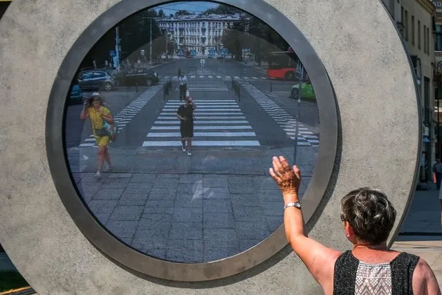 A woman waves to a real-time video portal connecting Lublin and Vilnius at the Lithuanian square on July 07, 2021 in Lublin, Poland. The virtual bridge allows people from the Lithuanian capital to interact with passersby at the “other end” of the portal, in Lublin located more than 550 km away.In the future, there are plans to also build portals connecting Vilnius to Reykjavik and London. (Photo by Omar Marques/Anadolu Agency via Getty Images)
